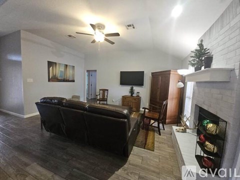 A living room with a black couch and a fireplace.