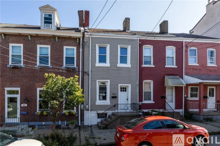 A row of houses with a red car parked in front of them.