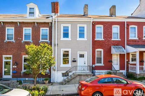 A row of houses with a red car parked in front of them.