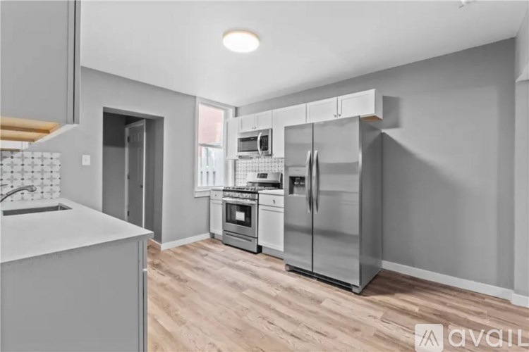 A modern kitchen with wooden floors and stainless steel appliances.