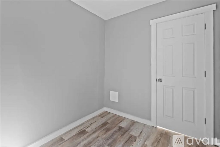 A room with a white door and wooden flooring.