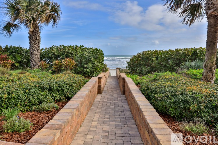A pathway with a brick border leads to the beach.