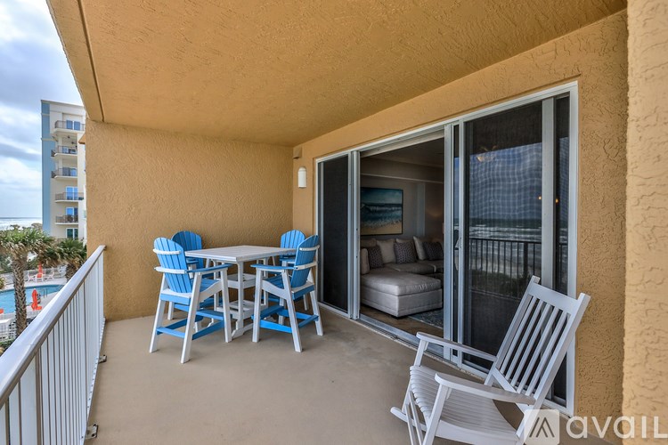 A balcony with a table and chairs overlooking a pool.