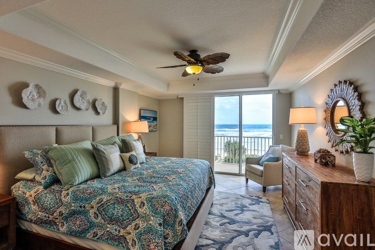 A bedroom with a large bed and a balcony overlooking the ocean.