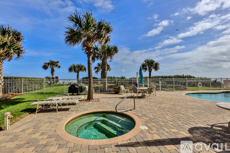 A pool surrounded by palm trees and a fence.