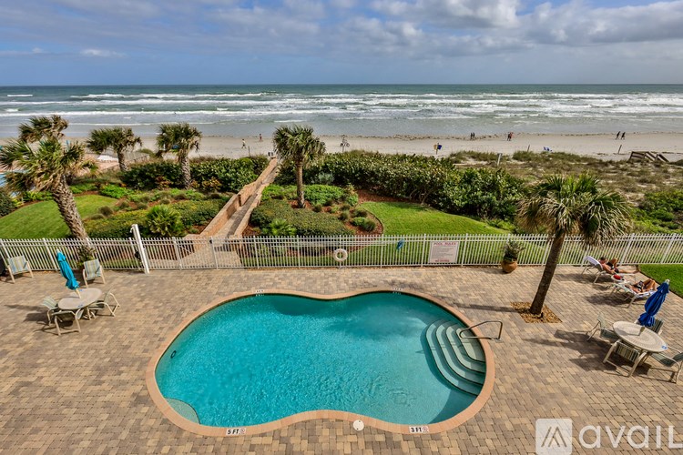 A pool surrounded by beach chairs and palm trees.