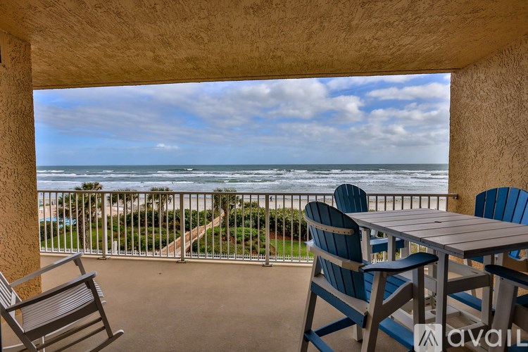 A balcony with a table and chairs overlooking the ocean.