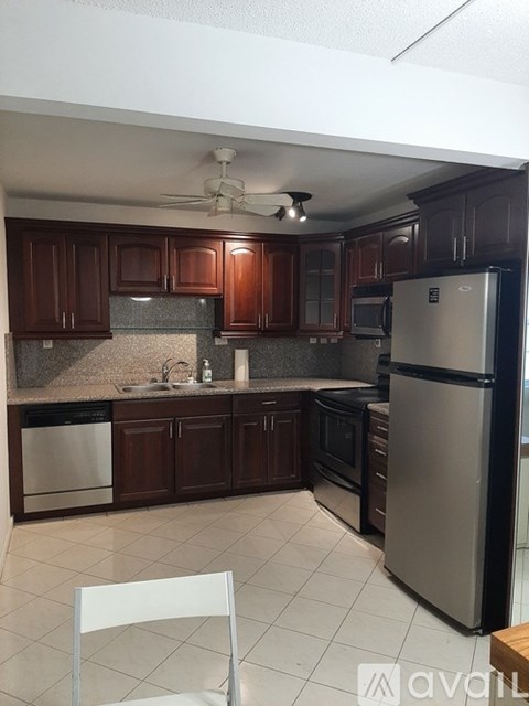 A kitchen with dark wood cabinets and a stainless steel refrigerator.