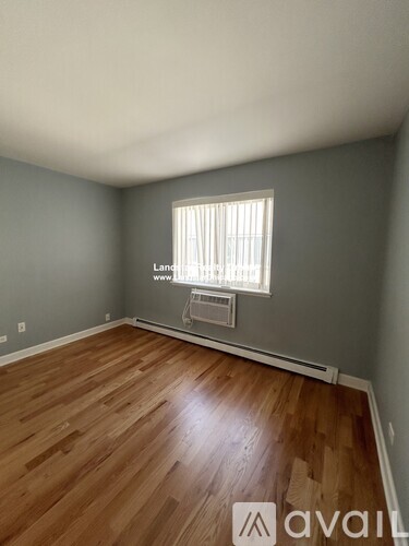 A room with wooden flooring and a window with blinds.