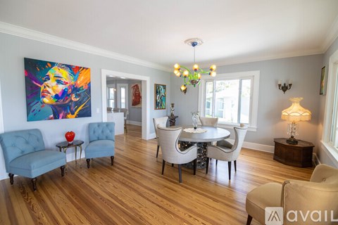 A living room with a blue chair and a painting on the wall.
