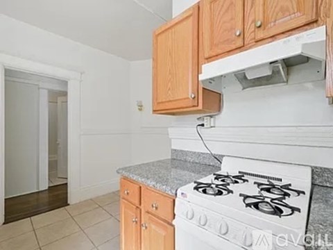 A kitchen with a white stove top oven and wooden cabinets.