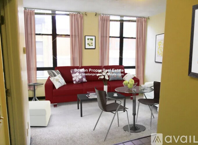 A living room with a red couch, a small table, and a window with pink curtains.