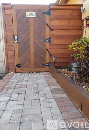 A wooden gate with a metal handle and a sign on it.