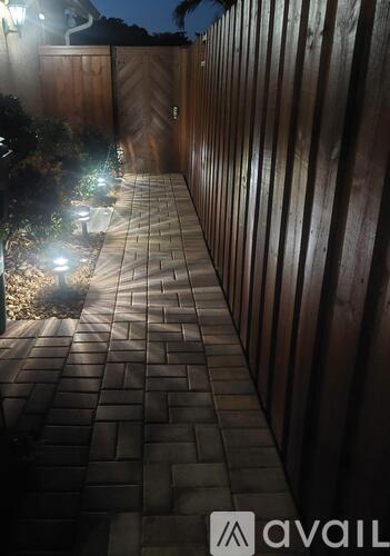 A pathway with lights on the side and a wooden fence on the other side.
