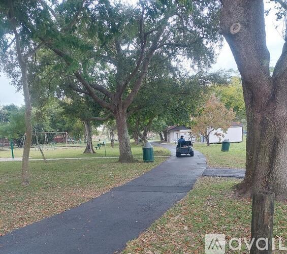 A park with a paved path and trees.