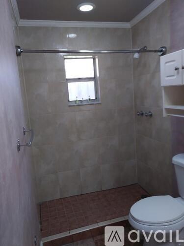 A bathroom with a toilet, a shower with a glass door, and a window.
