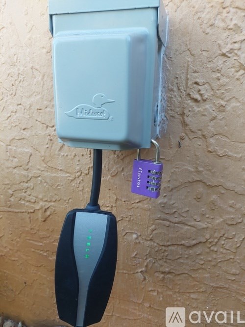 A wall-mounted device with a blue box and a black antennae.