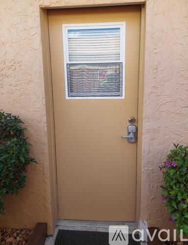 A yellow door with a window above it and a doormat in front.