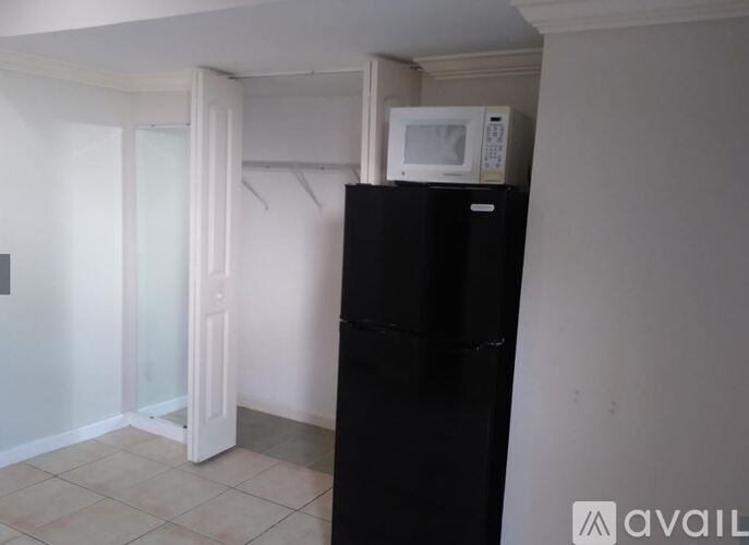 A black fridge in a room with a white door.