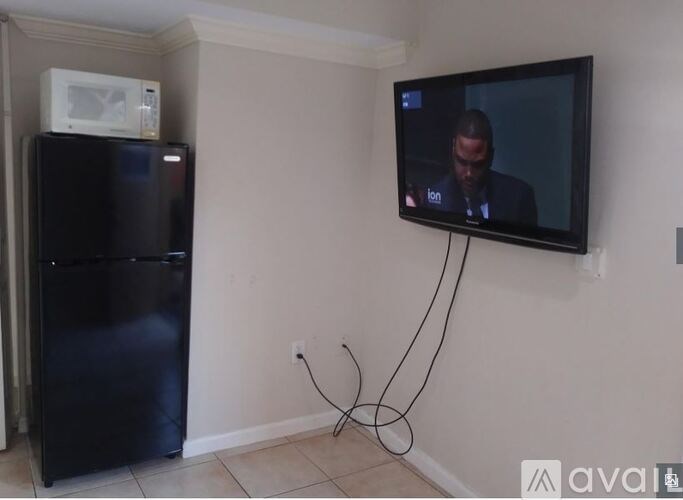 A black refrigerator with a white microwave on top of it.