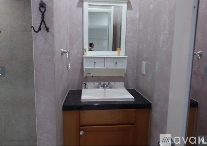 A bathroom with a sink, mirror, and cabinet.