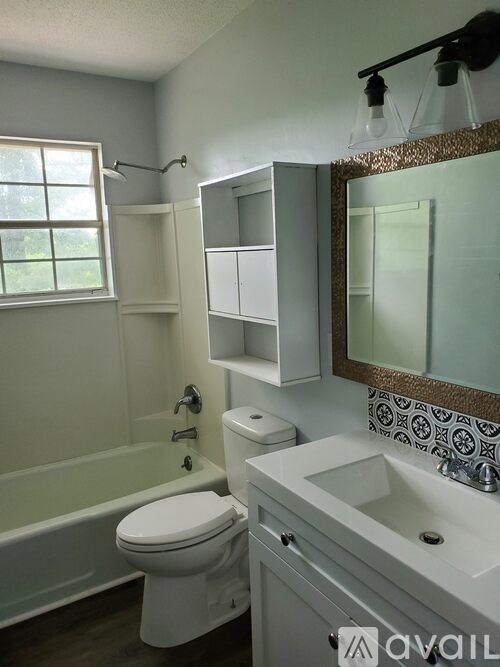 A bathroom with a toilet, sink, and mirror.