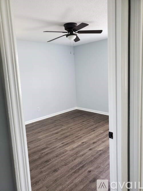 A room with a ceiling fan and wood flooring.