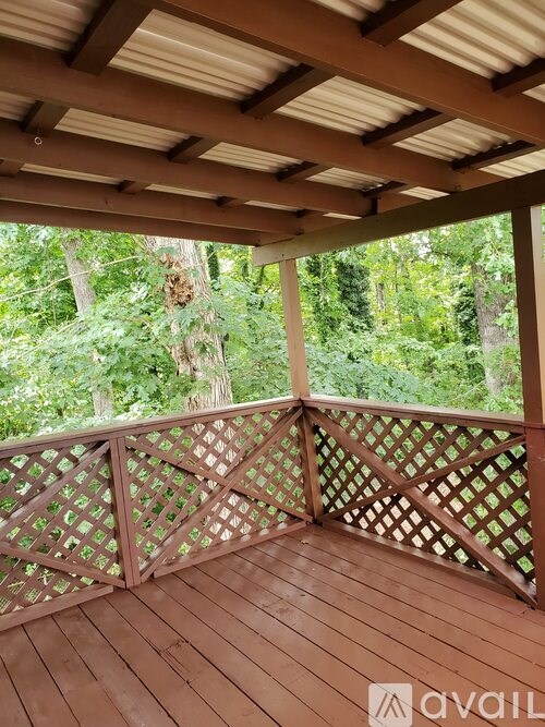 A wooden deck with a lattice design and a view of the forest.