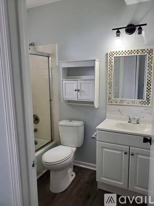 A white toilet is in a bathroom with a white sink and mirror.