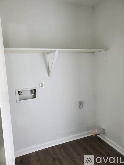 A small room with a white wall and a wooden floor.