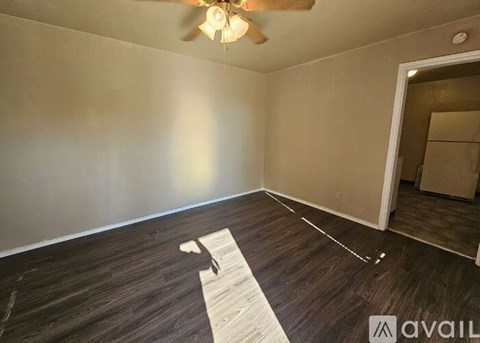 A room with a ceiling fan and wooden flooring.