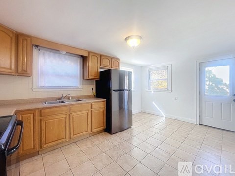 A kitchen with wooden cabinets and a black refrigerator.