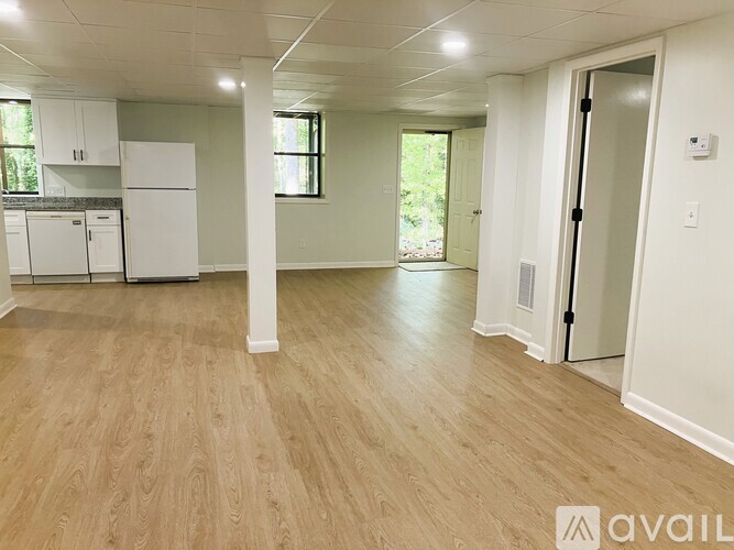A spacious room with wooden flooring and white walls.