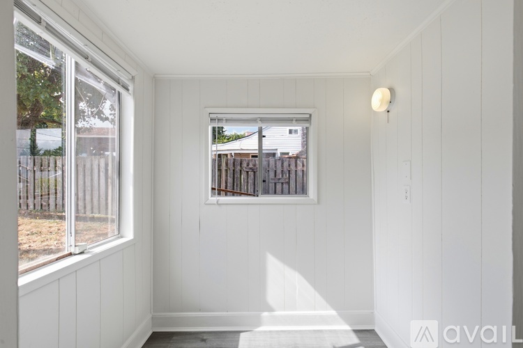 A white room with a window and a wall light.