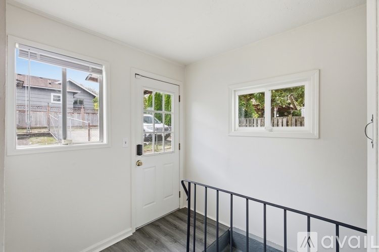 A white room with a black railing and a window overlooking a backyard.