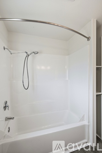 A white bathroom with a glass shower door and a silver shower head.