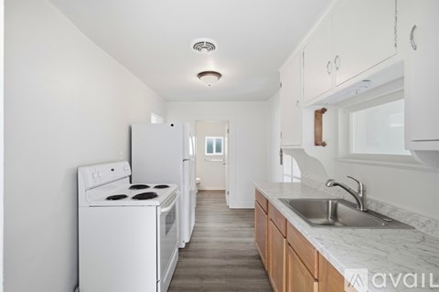 A white kitchen with a stove, sink and cabinets.