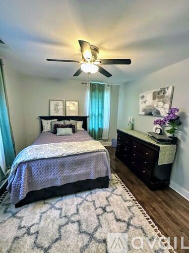 A bedroom with a bed, dresser, and ceiling fan.