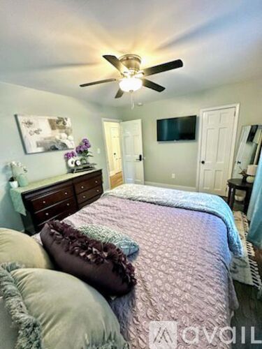 A bedroom with a bed, dresser, and ceiling fan.