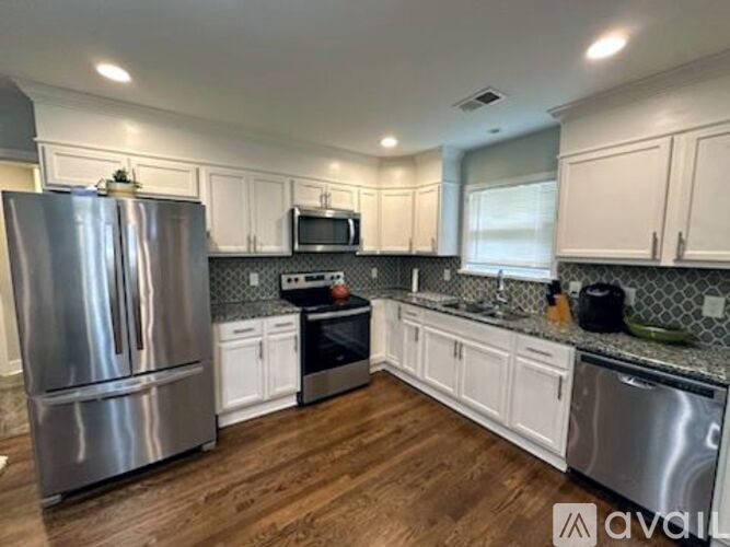 A kitchen with white cabinets and a stainless steel refrigerator.