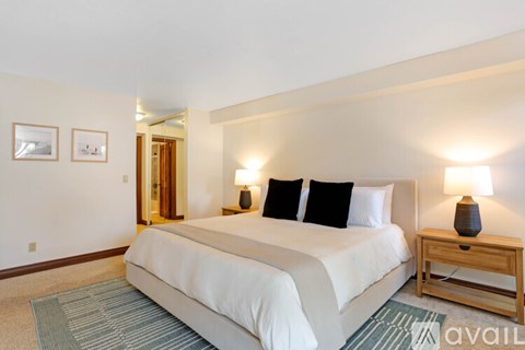 A bedroom with a large bed and two lamps.
