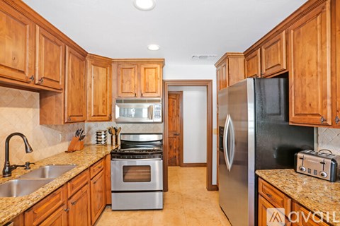 A kitchen with wooden cabinets and a black refrigerator.