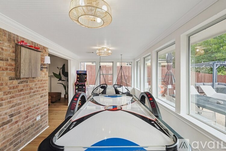 A room with a surfboard on the wall and a window showing a pool.