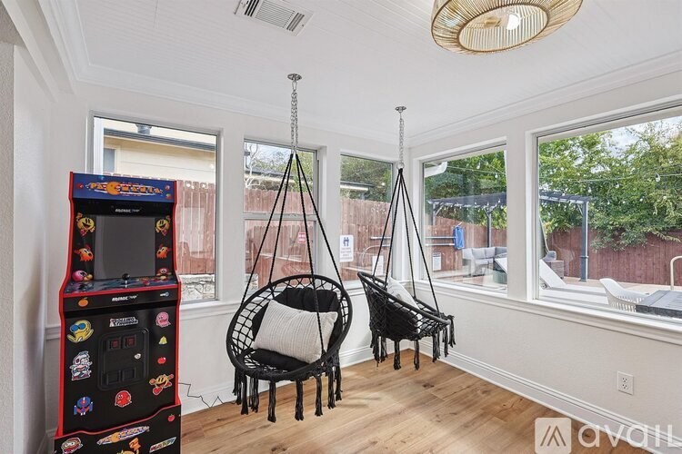 A room with a swing hanging from the ceiling and a small arcade machine.