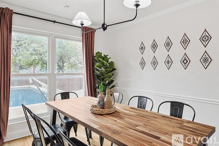 A wooden table with a plant and a vase on it in front of a wall with diamond patterned wallpaper.
