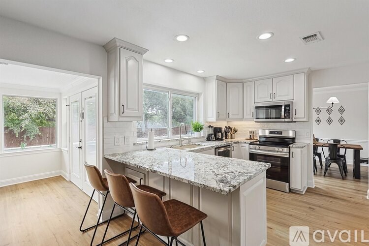 A kitchen with a marble countertop and wooden floors.