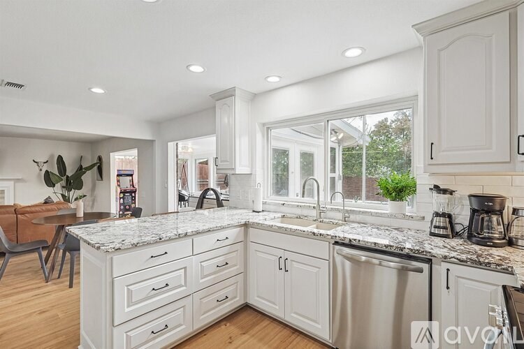 A modern kitchen with white cabinets and a marble countertop.
