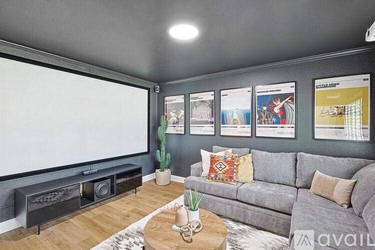 A living room with a grey couch, a coffee table, a whiteboard, and pictures on the wall.