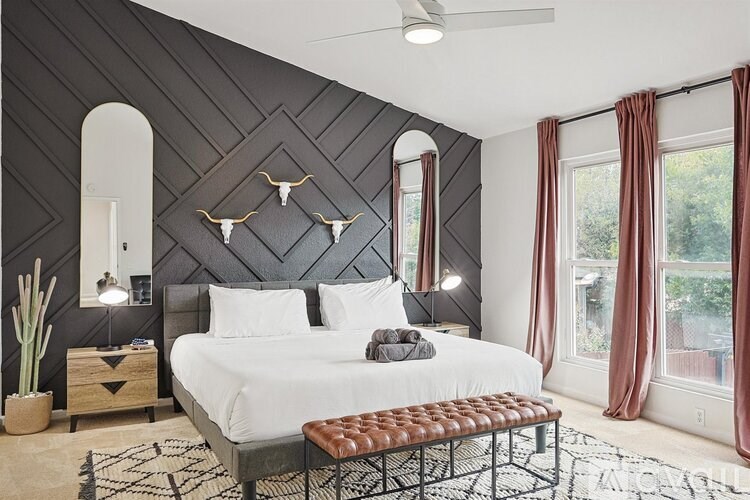 A bedroom with a large bed and a rug on the floor.