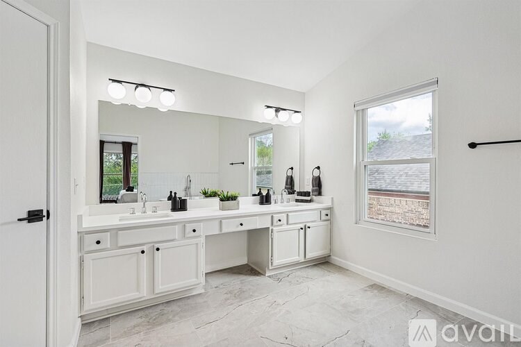 A white bathroom with a large mirror and a window overlooking a field.